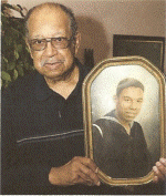 Retired Master Chief Boatswain’s Mate Robert Hammond holds a framed colorized 1942 photo of himself as a seaman recruit at Manhattan Beach. (Courtesy of Robert Hammond)